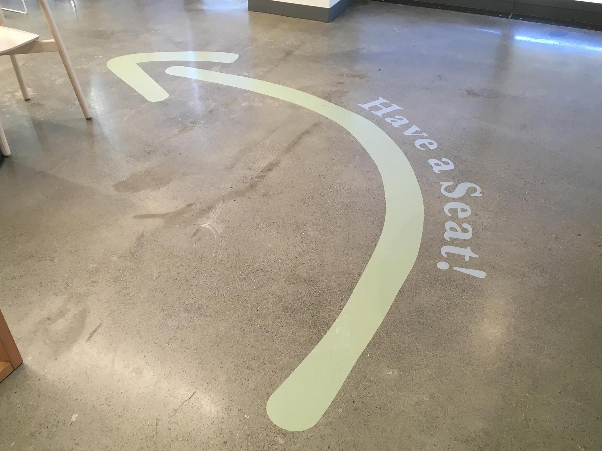 Have a Seat wayfinding arrow painted on West Harvest cafe's concrete floor near seating