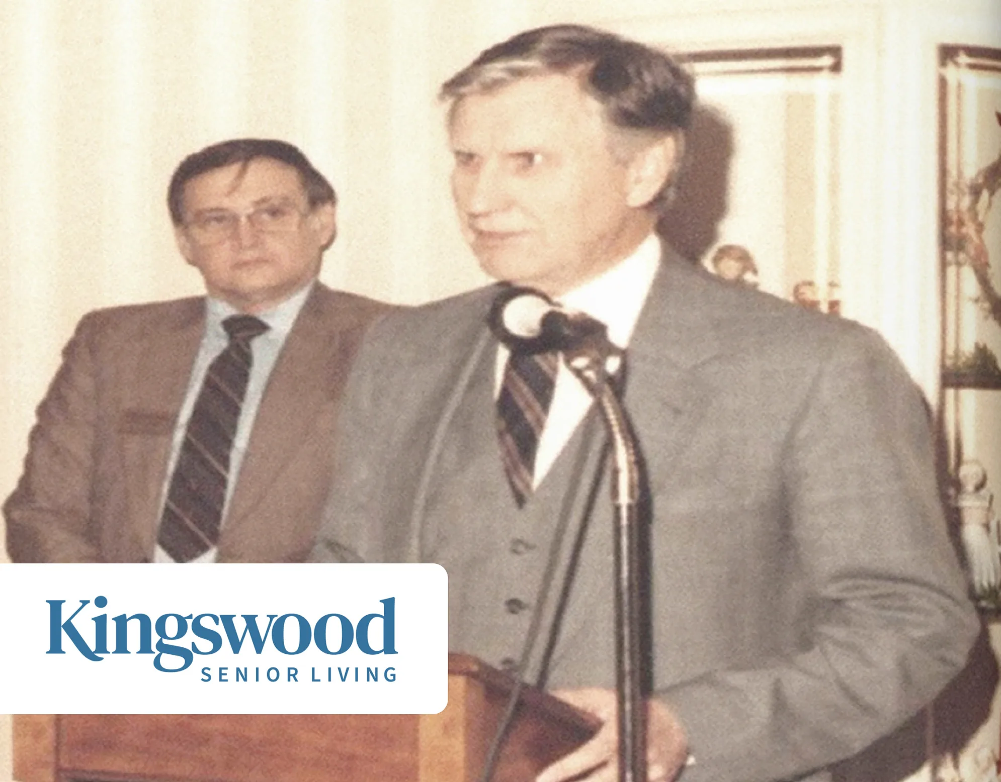 A Vision That Grew cover: sepia vintage photo of two men in suits, one speaking at a podium microphone