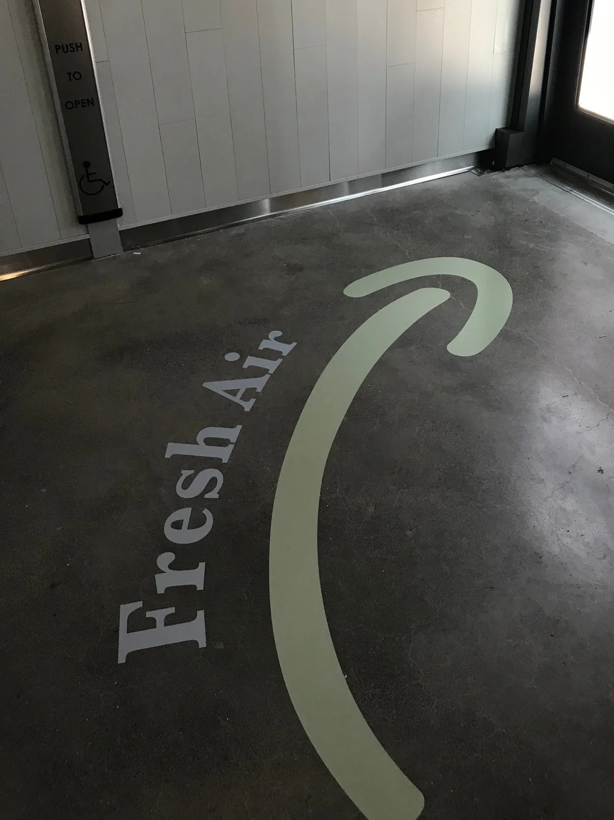 Fresh Air floor graphic arrow pointing toward an accessible exit door at West Harvest