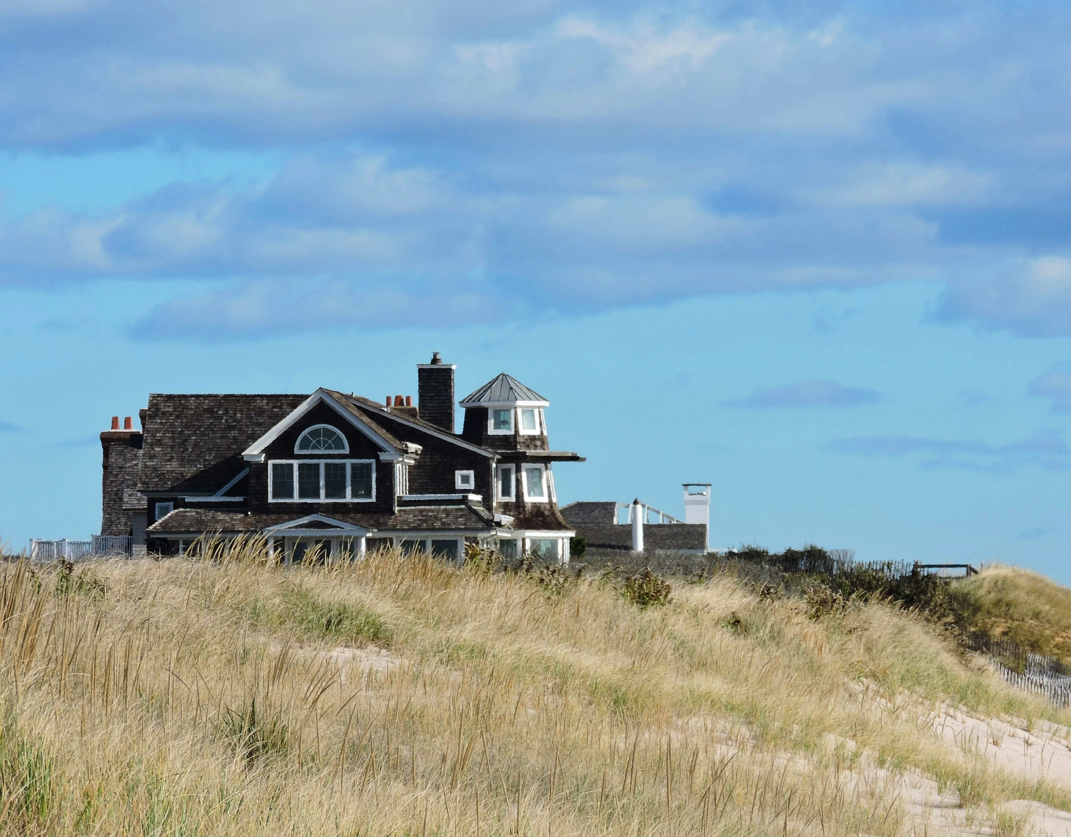 Project Montauk cover: shingled beach house atop a grassy dune under a partly cloudy blue sky