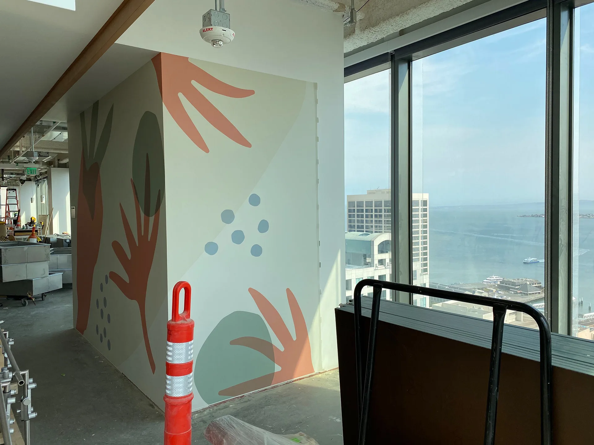 Painted botanical mural on an angled wall column with a floor-to-ceiling view of San Francisco Bay