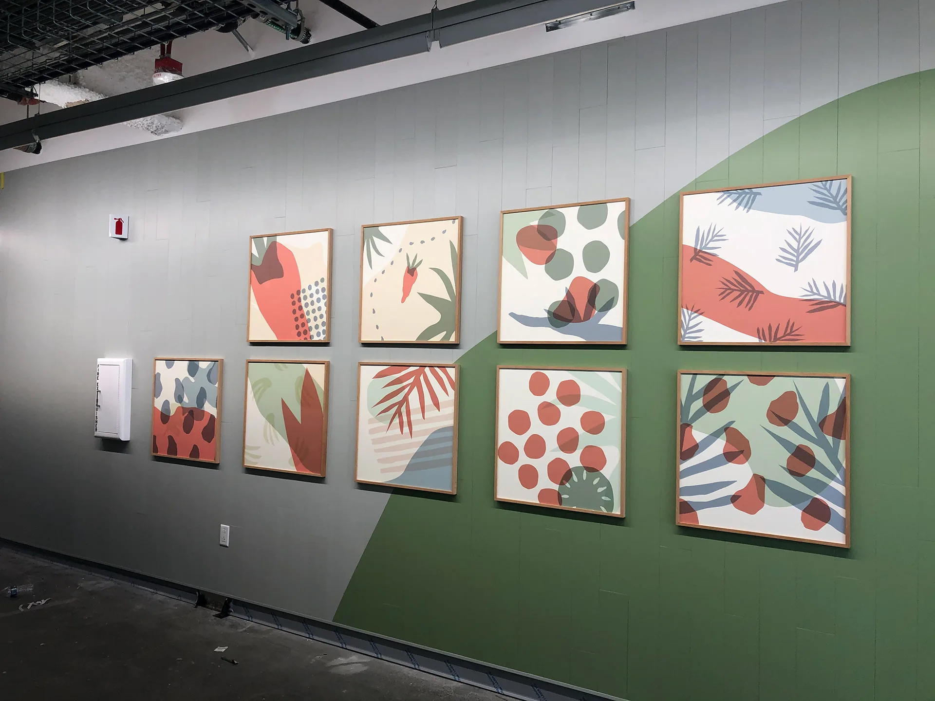 Eight framed produce-pattern art prints hung on a green and cream painted mural wall at West Harvest