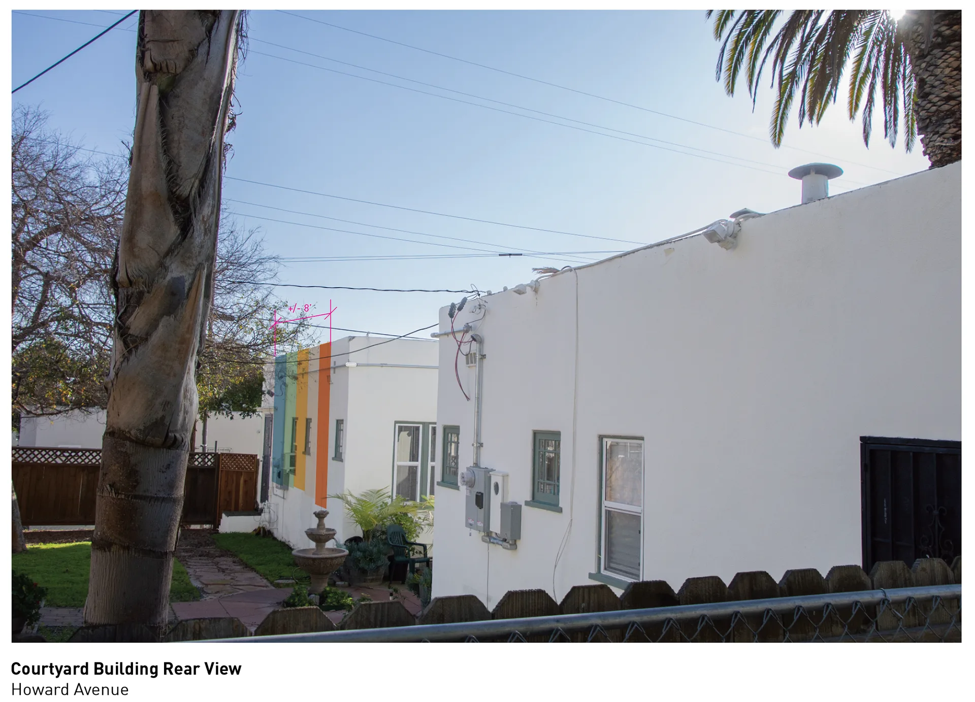 Rear view of the courtyard building's white wall with the rainbow-striped wall visible in the background