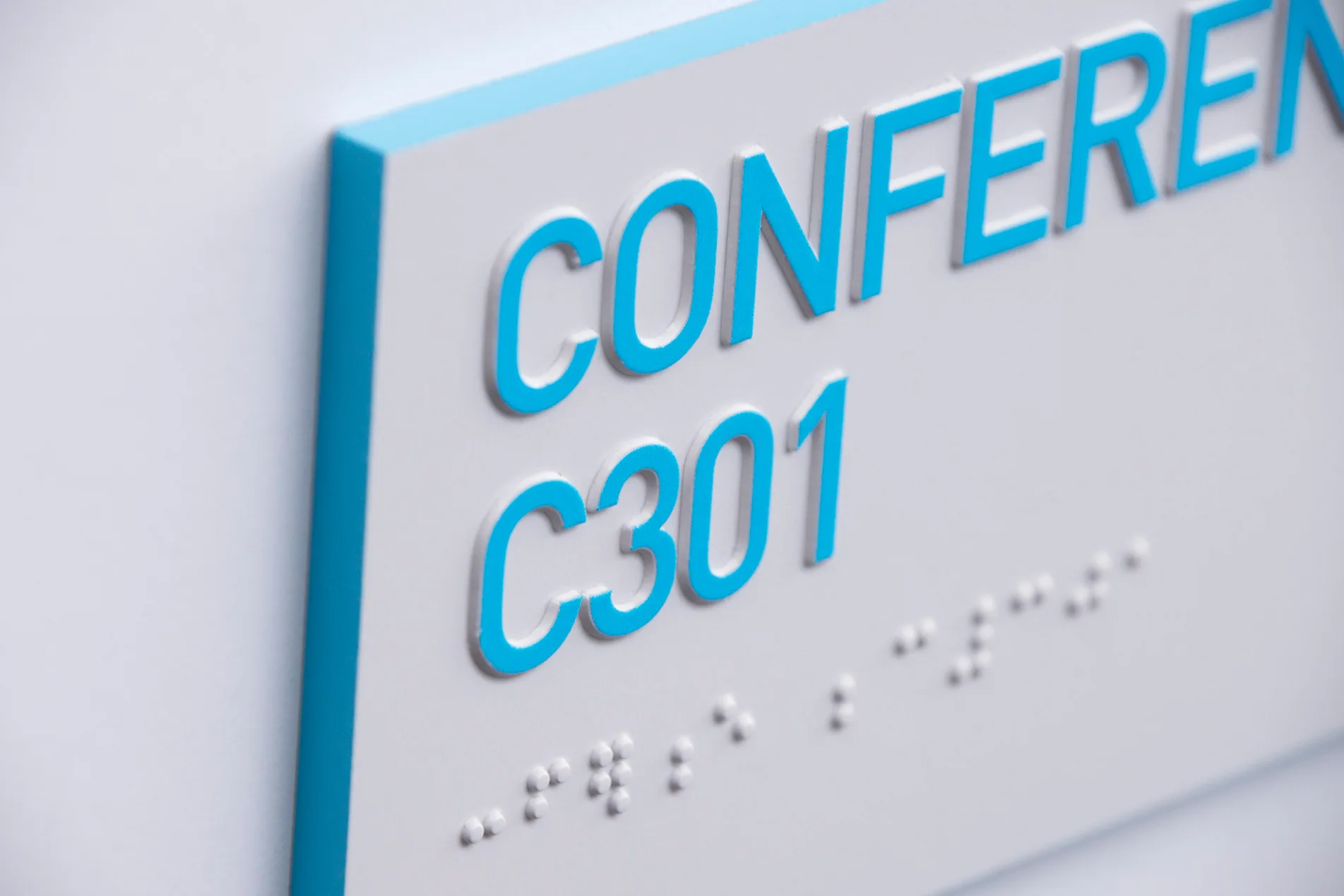 Angled close-up of the Conference C301 sign showing its blue edge detail and raised braille dots