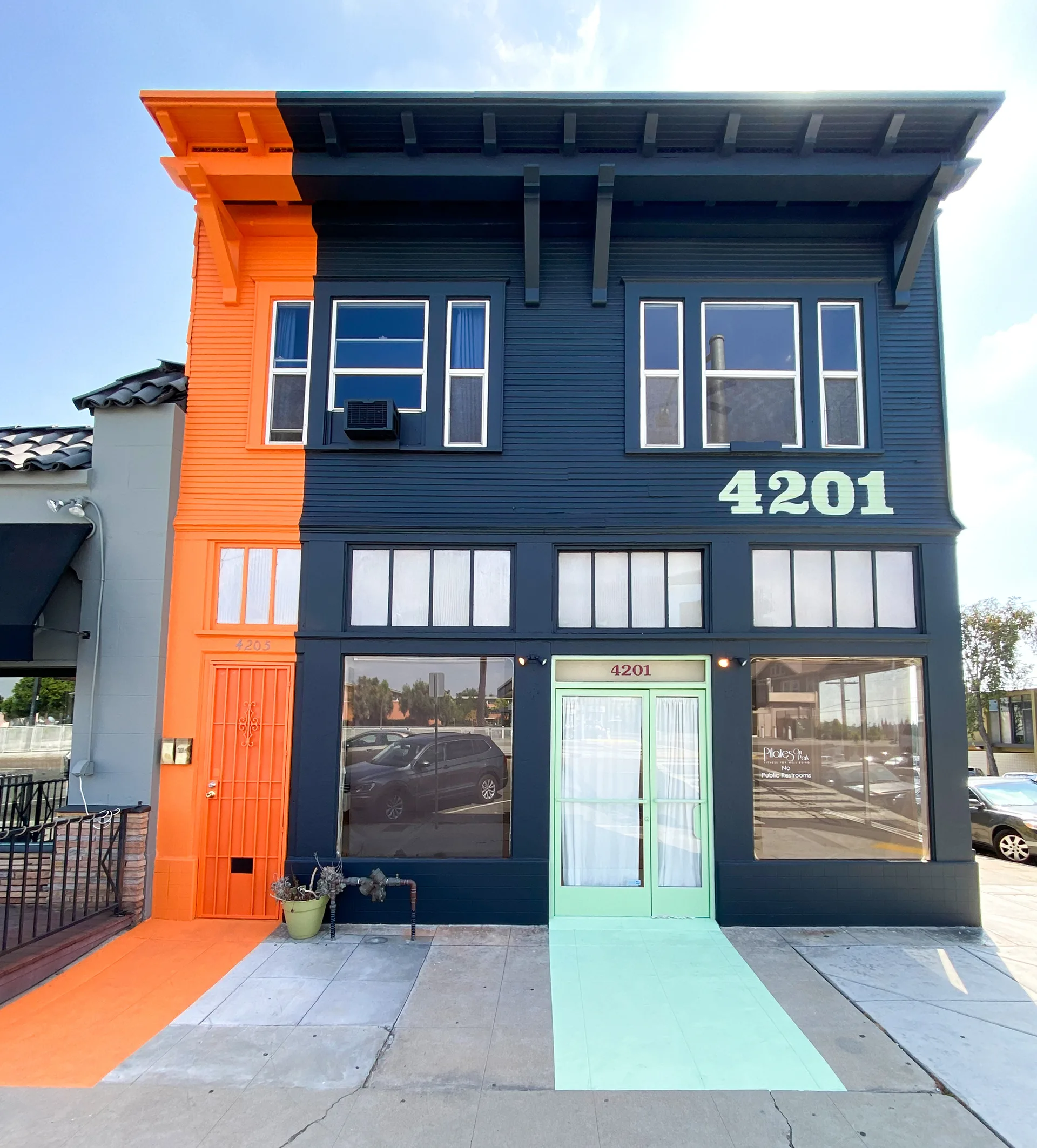 4201 Park Boulevard storefront painted half orange, half navy blue, with a mint green entry ramp and glass door