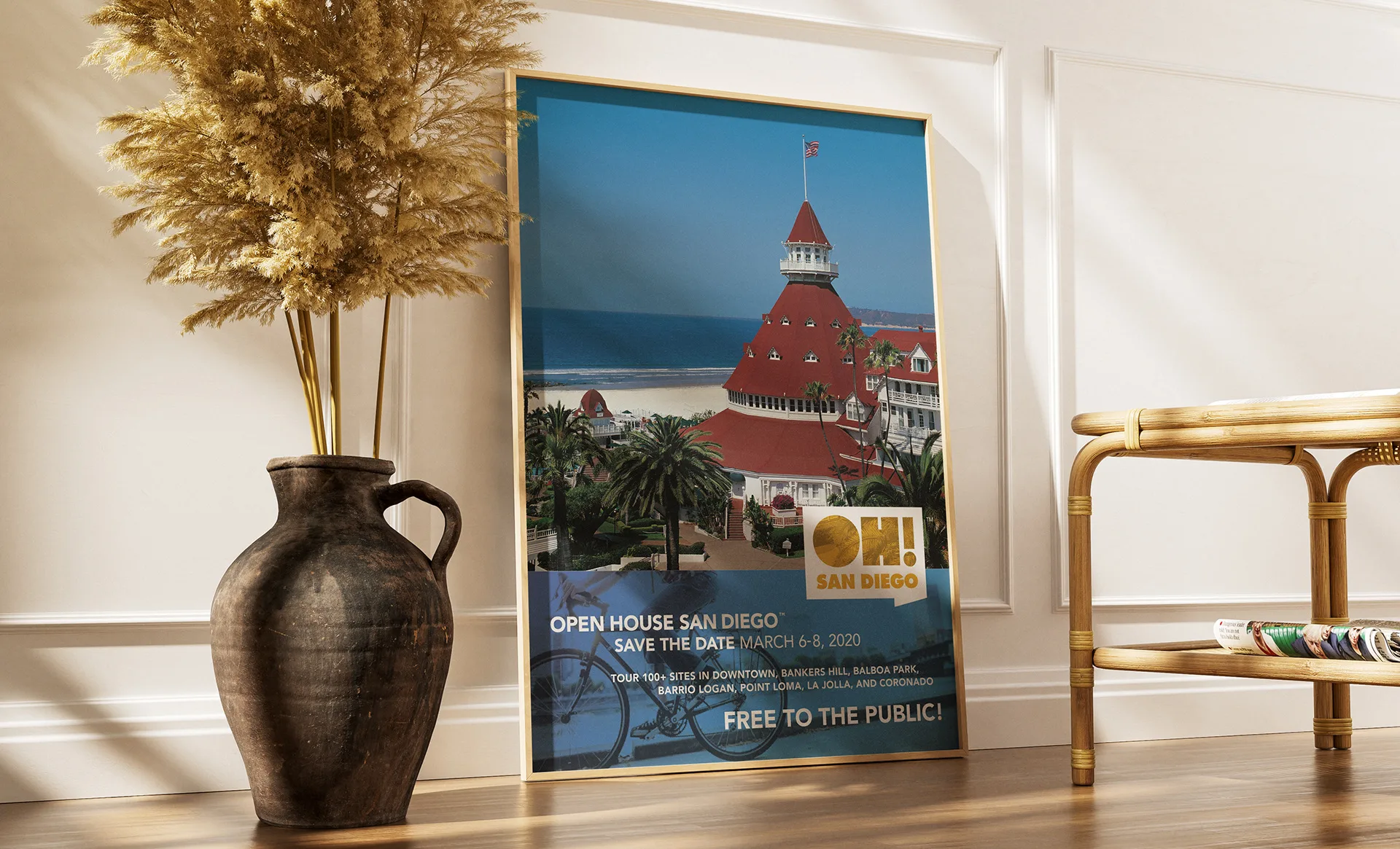 Framed OH! San Diego poster of the Hotel del Coronado leaning against a wall beside a ceramic vase