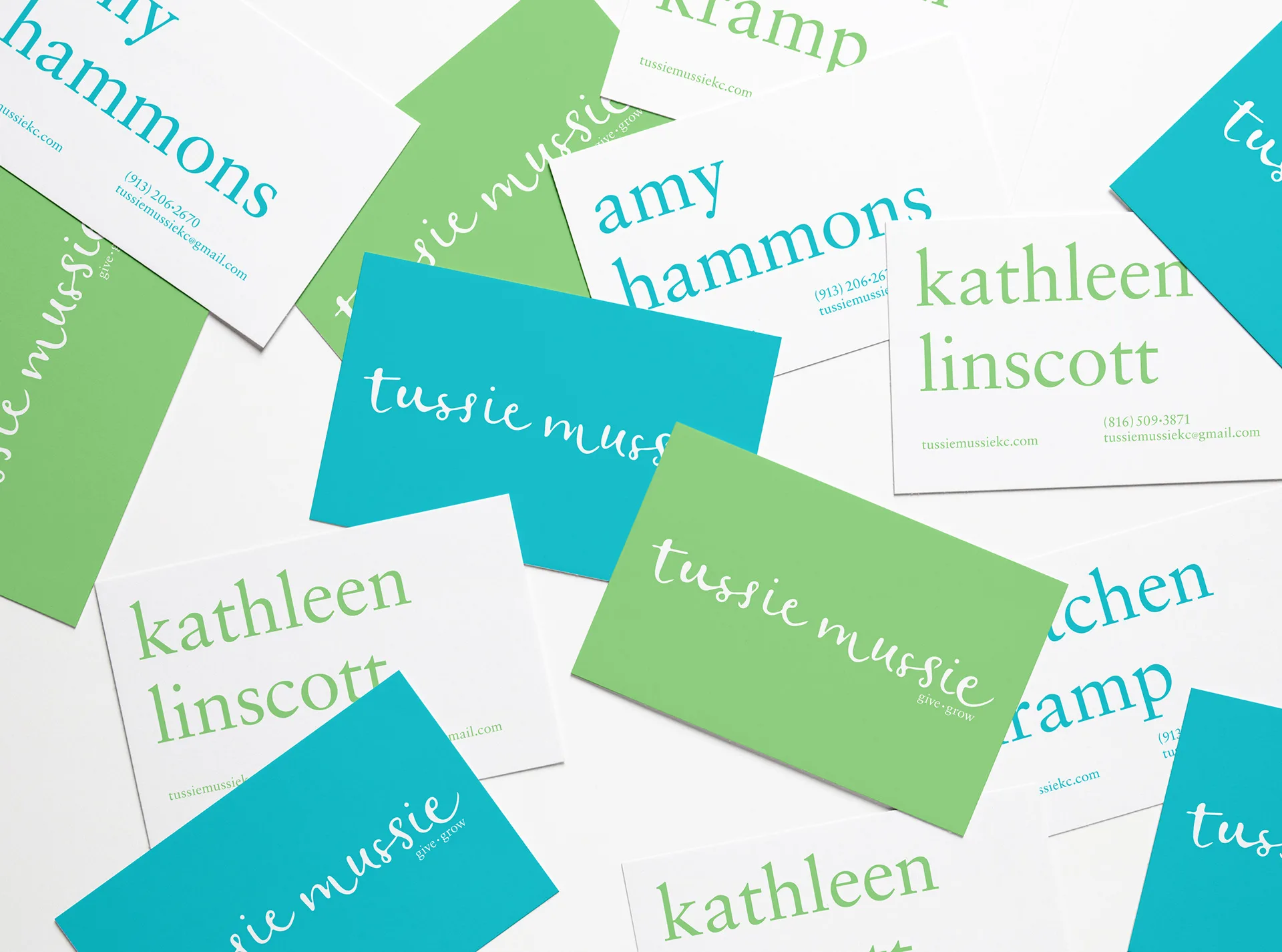 Scattered Tussie Mussie business cards in green, teal, and white featuring the cursive wordmark and staff names